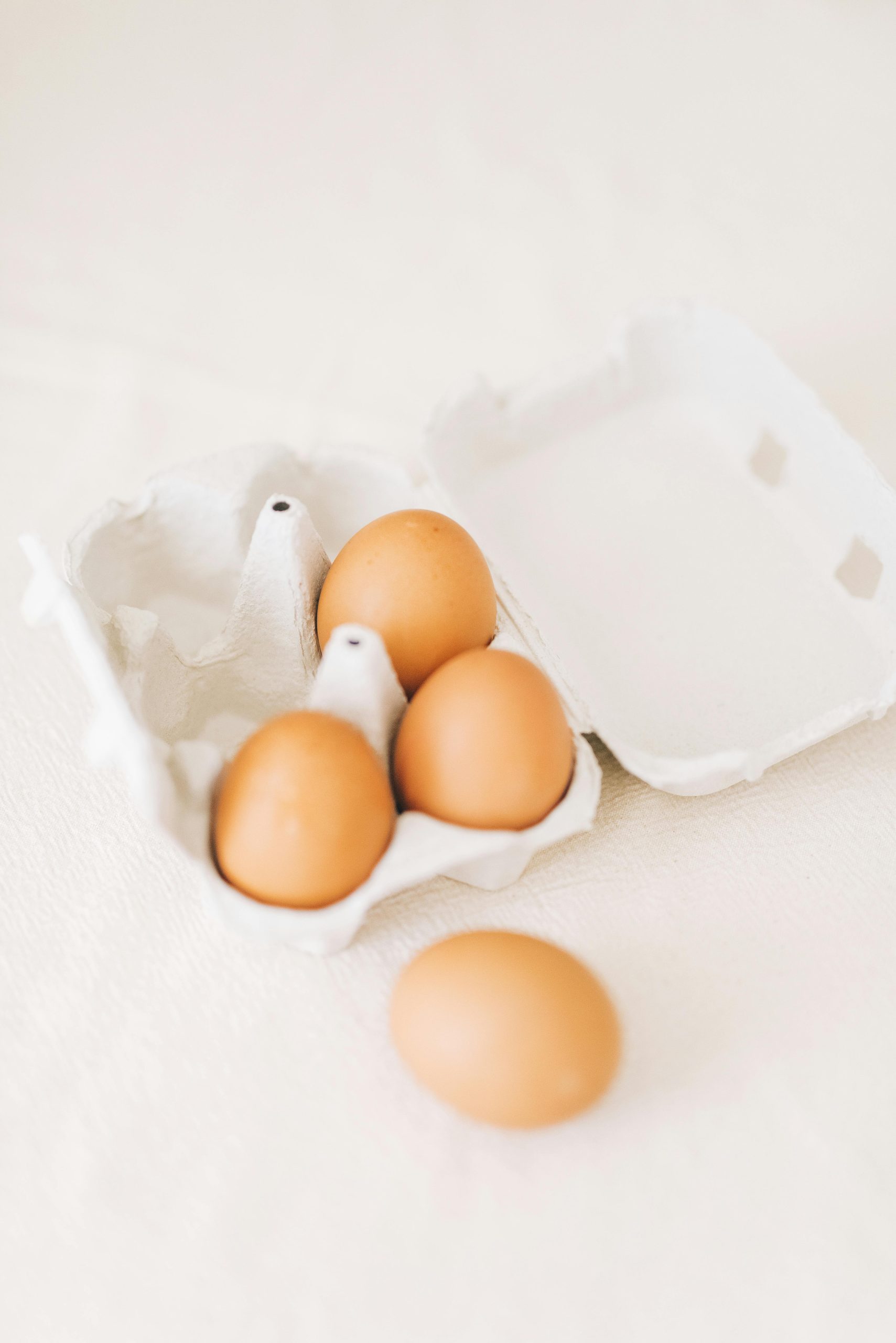 Brown eggs in an open carton against a soft background, highlighting simplicity and freshness. Œufs bruns dans une boîte ouverte sur un fond doux, mettant en valeur la simplicité et la fraîcheur.