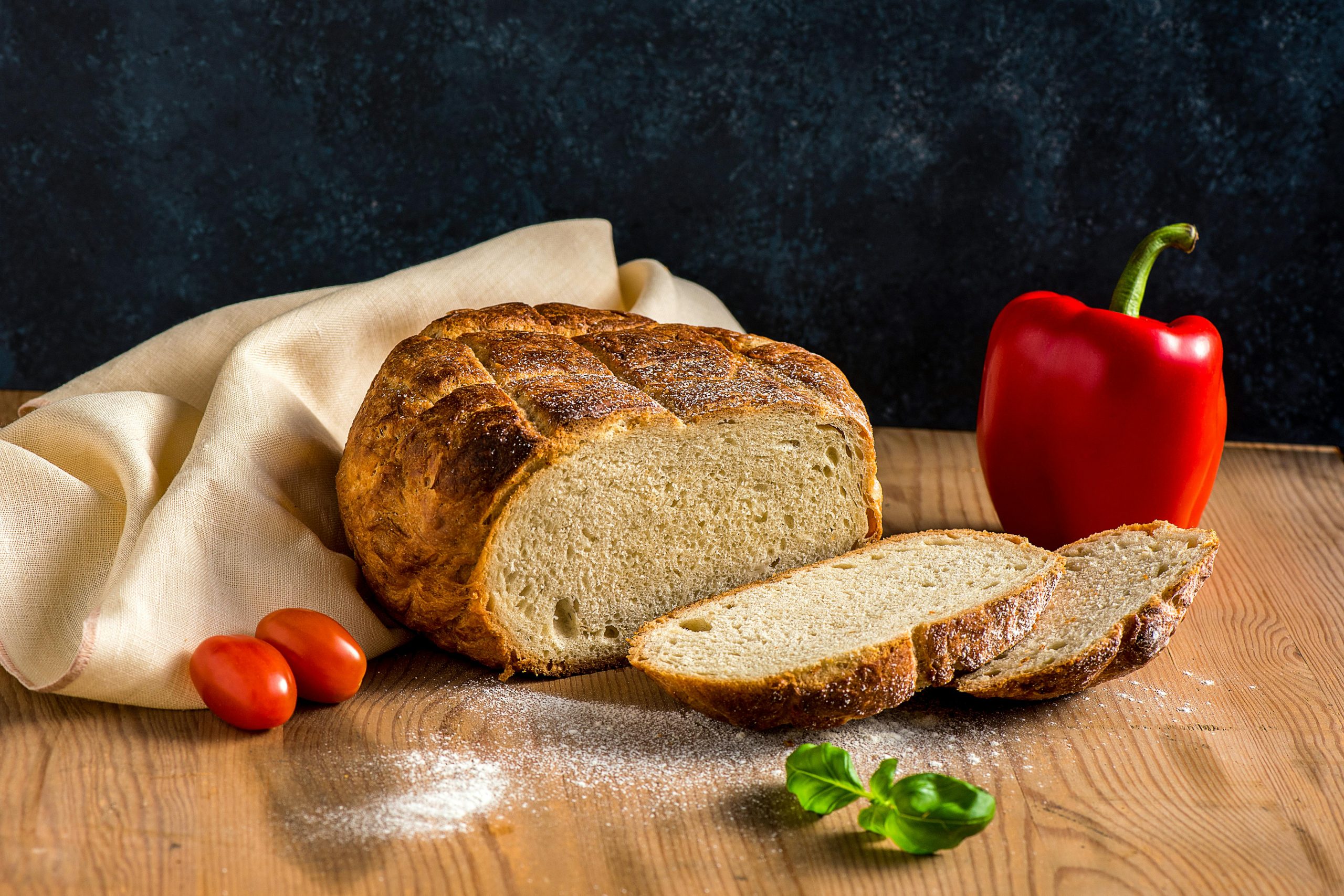 Délicieux pain au levain fraîchement cuit avec des tomates et du poivre sur une table en bois rustique.