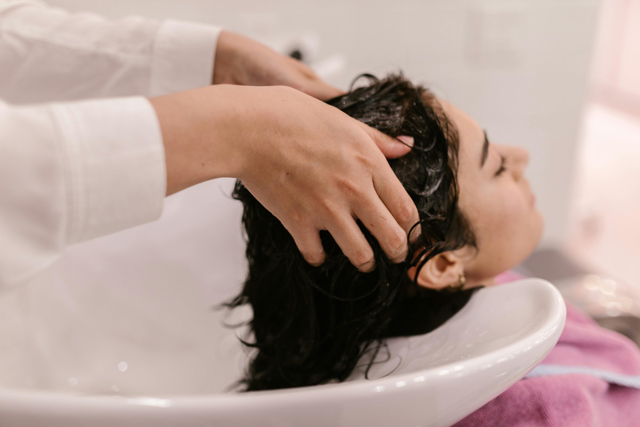 Une femme profite d'un shampoing relaxant dans un salon, capturée dans un cadre intérieur chaleureux.