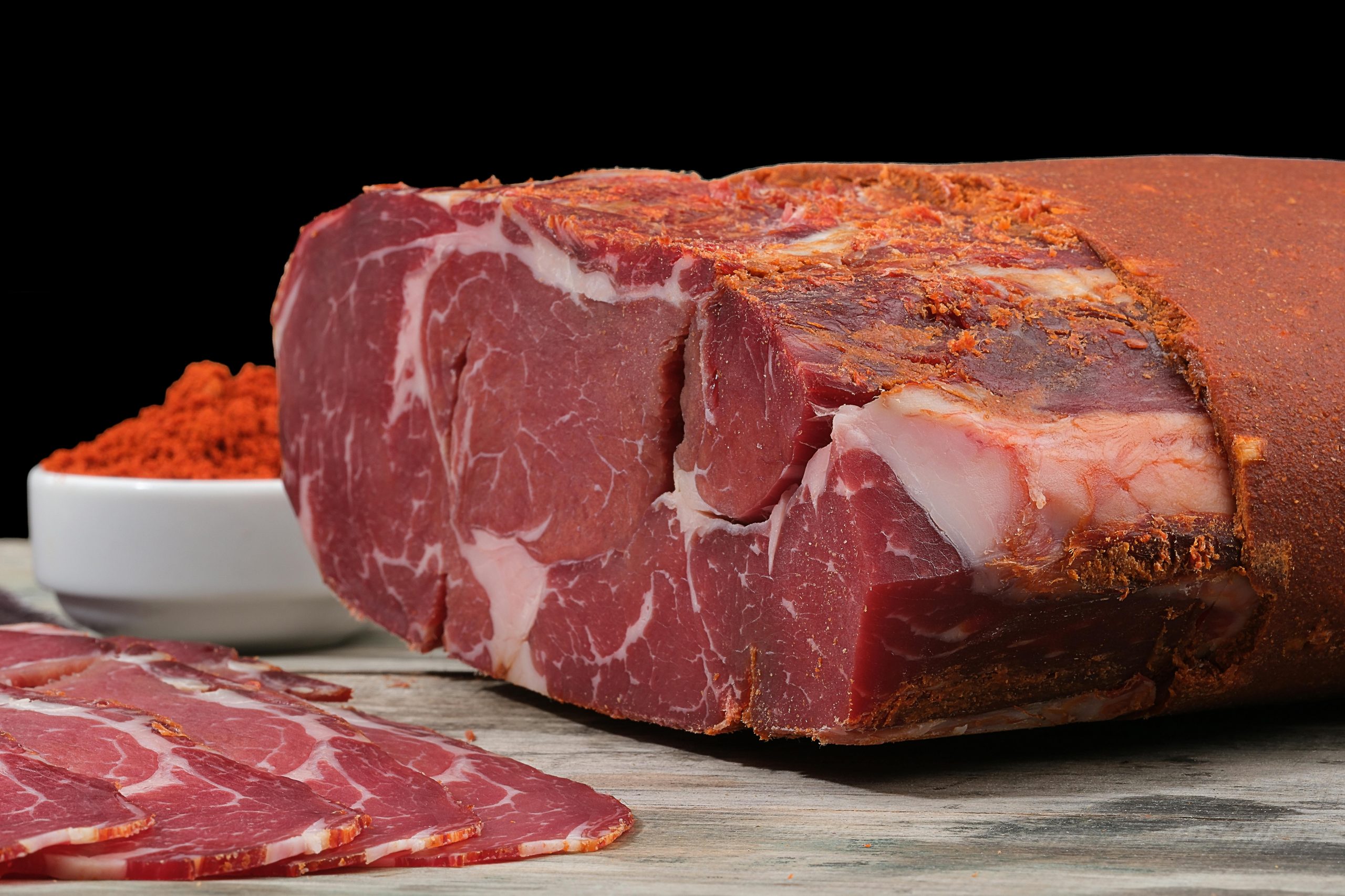 Close-up de bœuf séché avec du paprika sur une surface en bois rustique, mettant en valeur des textures vibrantes.