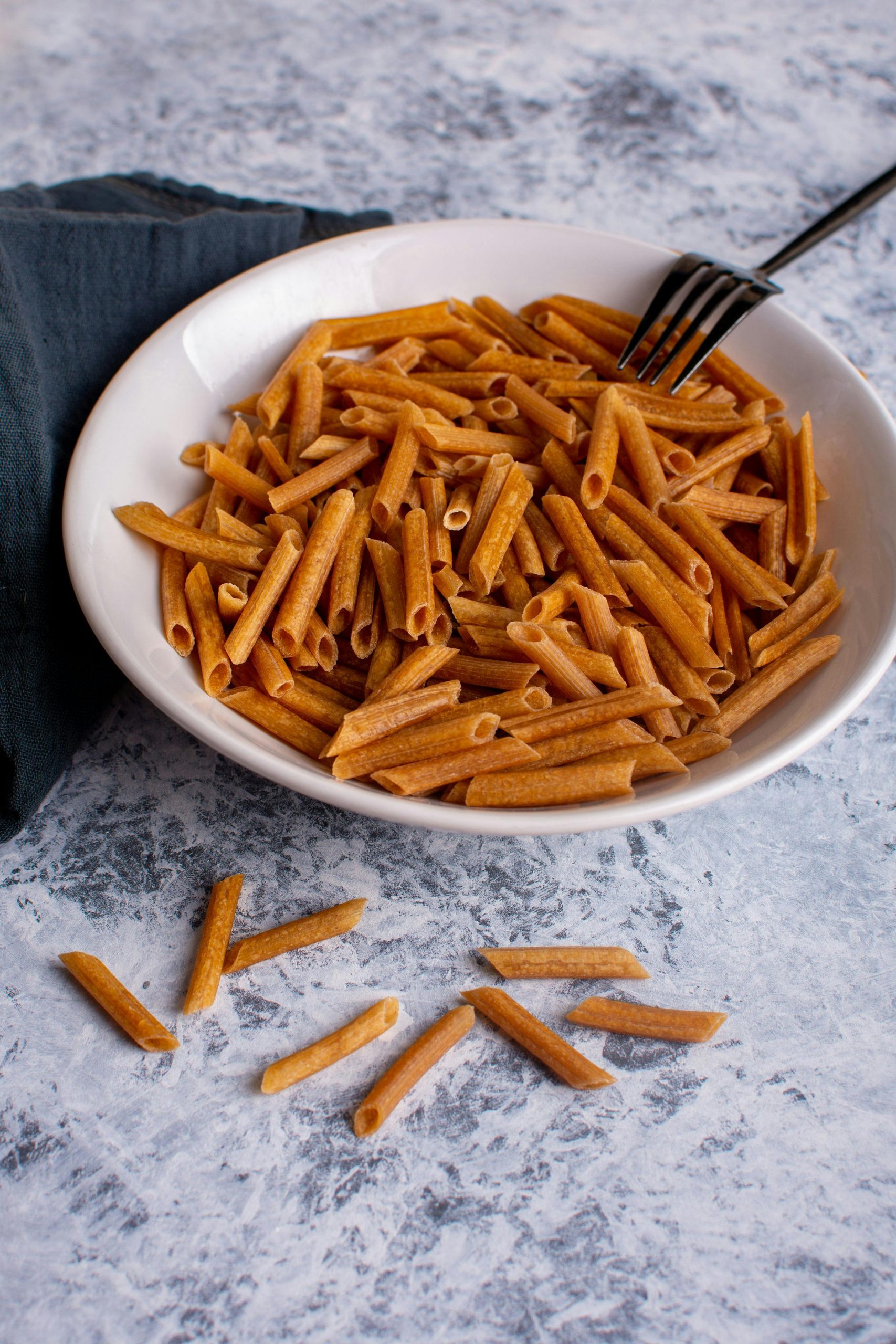 Un bol de penne complet posé sur une surface en marbre, parfait pour un usage culinaire.