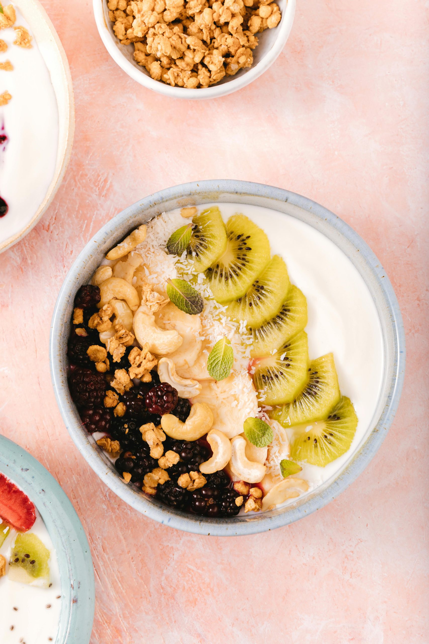 Delicieux bol de yaourt garni de kiwi, de mûres, de noix de cajou et de granola.