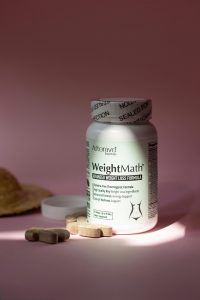 WeightMath flacon de complément vitaminé pour la gestion du poids avec des pilules sur une surface rose