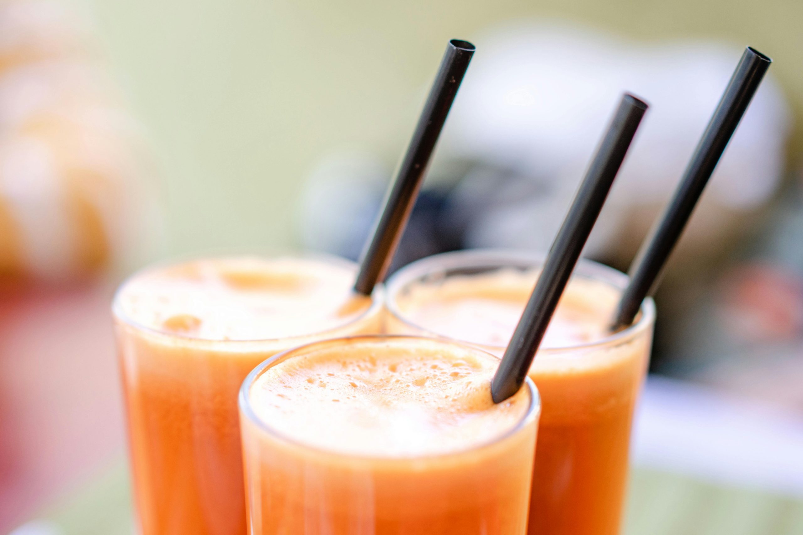 Gros plan sur un jus de carotte rafraîchissant servi dans des verres avec des pailles noires, parfait pour une collation saine.