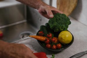 A close-up of fresh vegetables including broccoli, lemon, and tomatoes in a kitchen. Gros plan de légumes frais dont du brocoli, du citron et des tomates dans une cuisine.