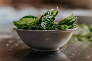 Close-up of fresh spinach leaves in a ceramic bowl, perfect for healthy eating themes. Gros plan sur des feuilles d'épinards frais dans un bol en céramique, parfait pour les thèmes d'alimentation saine.