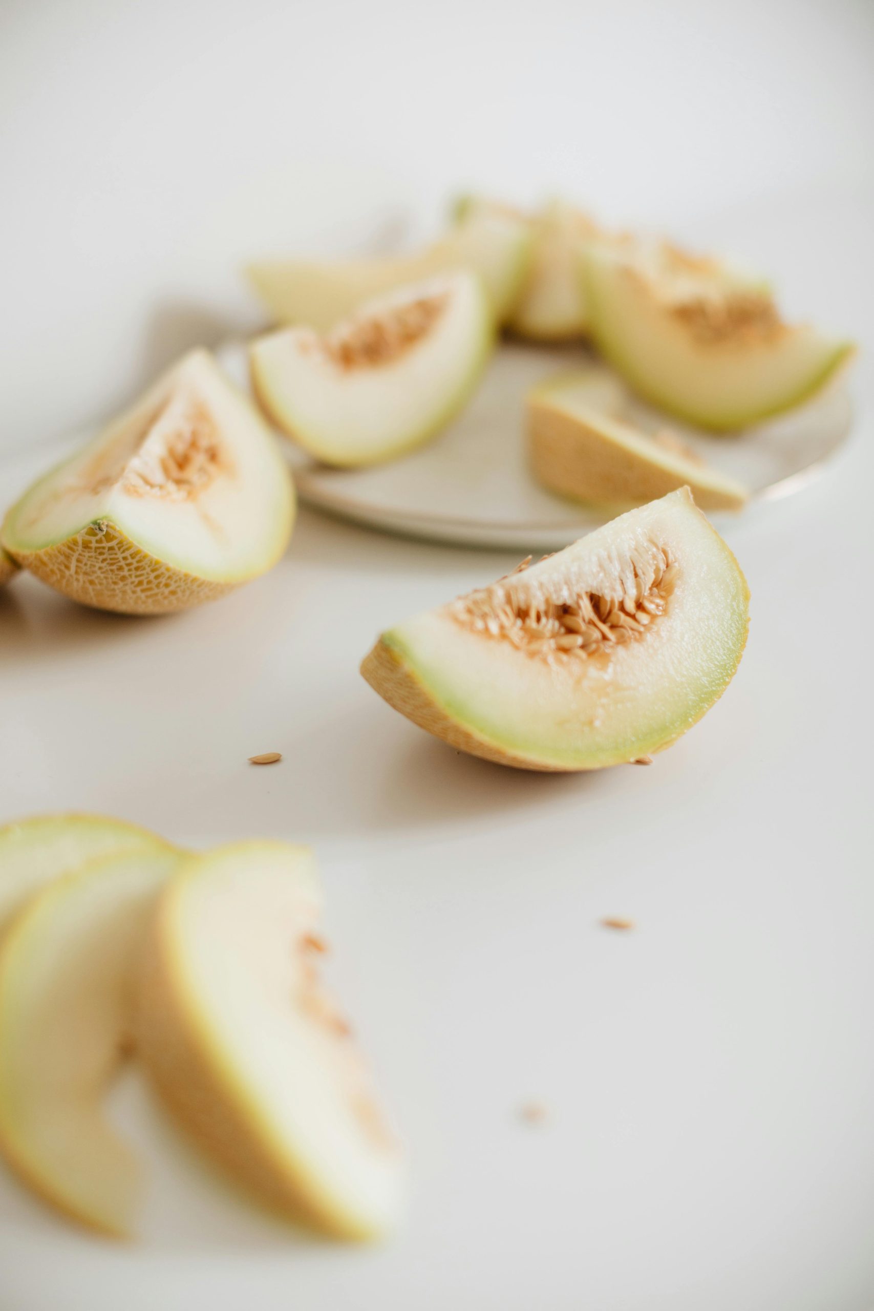 Close-up of sliced melon pieces on a white surface, showcasing their freshness and vibrant color. Gros plan de morceaux de melon tranchés sur une surface blanche, mettant en avant leur fraîcheur et leur couleur éclatante.