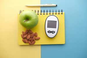Flat lay of diabetes tools, green apple, almonds, and notebook for health planning. Mise à plat des outils du diabète, pomme verte, amandes et carnet de planification sanitaire.