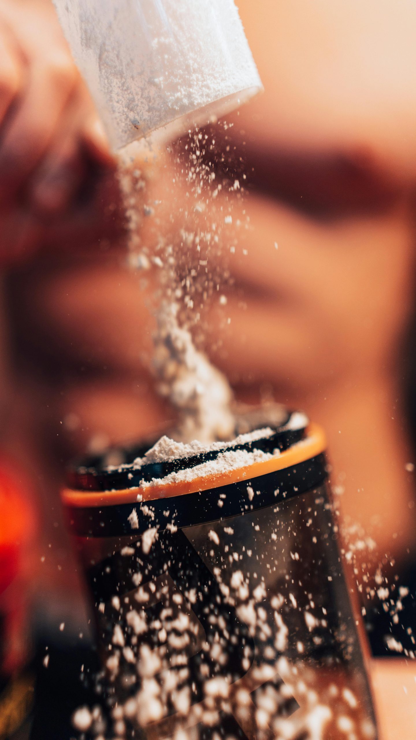 Dynamic shot of protein powder being added to a shaker, fitness concept. Photo dynamique de poudre de protéine versée dans un shaker, concept fitness.