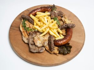 Savory mixed grill with meats, sausages, and fries on a wooden platter. Grillade mixte savoureuse avec viandes, saucisses et frites sur un plateau en bois.