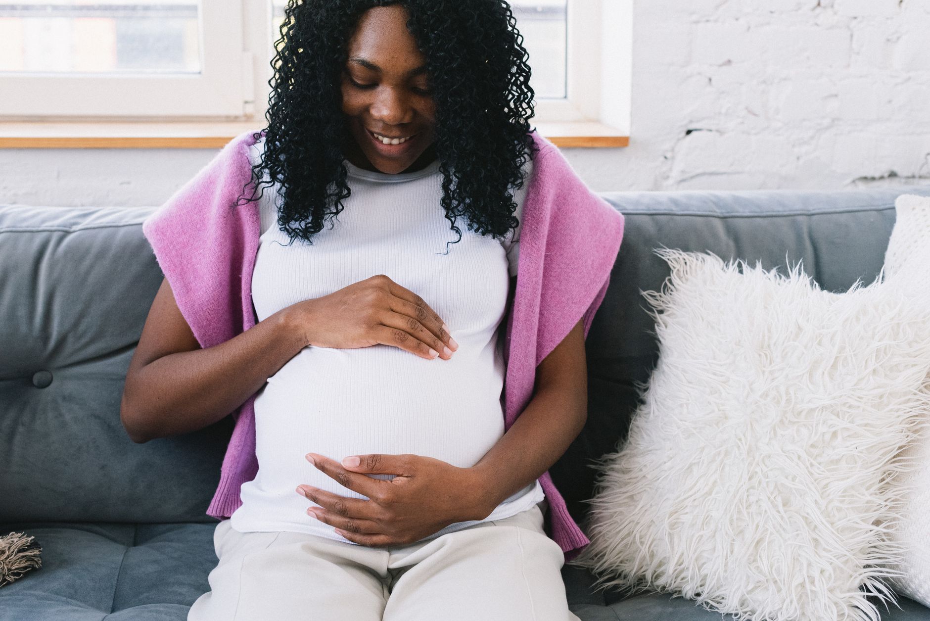 Femme enceinte assise sur un canapé, la main posée sur son ventre