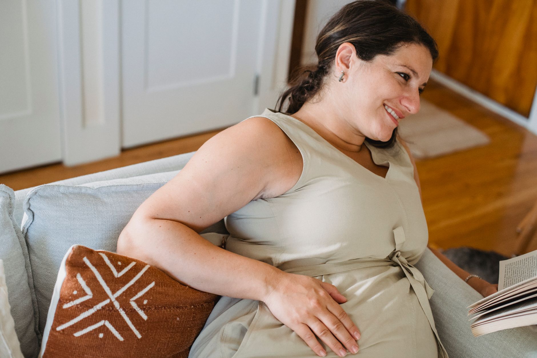 Femme enceinte souriante en train de lire sur un canapé