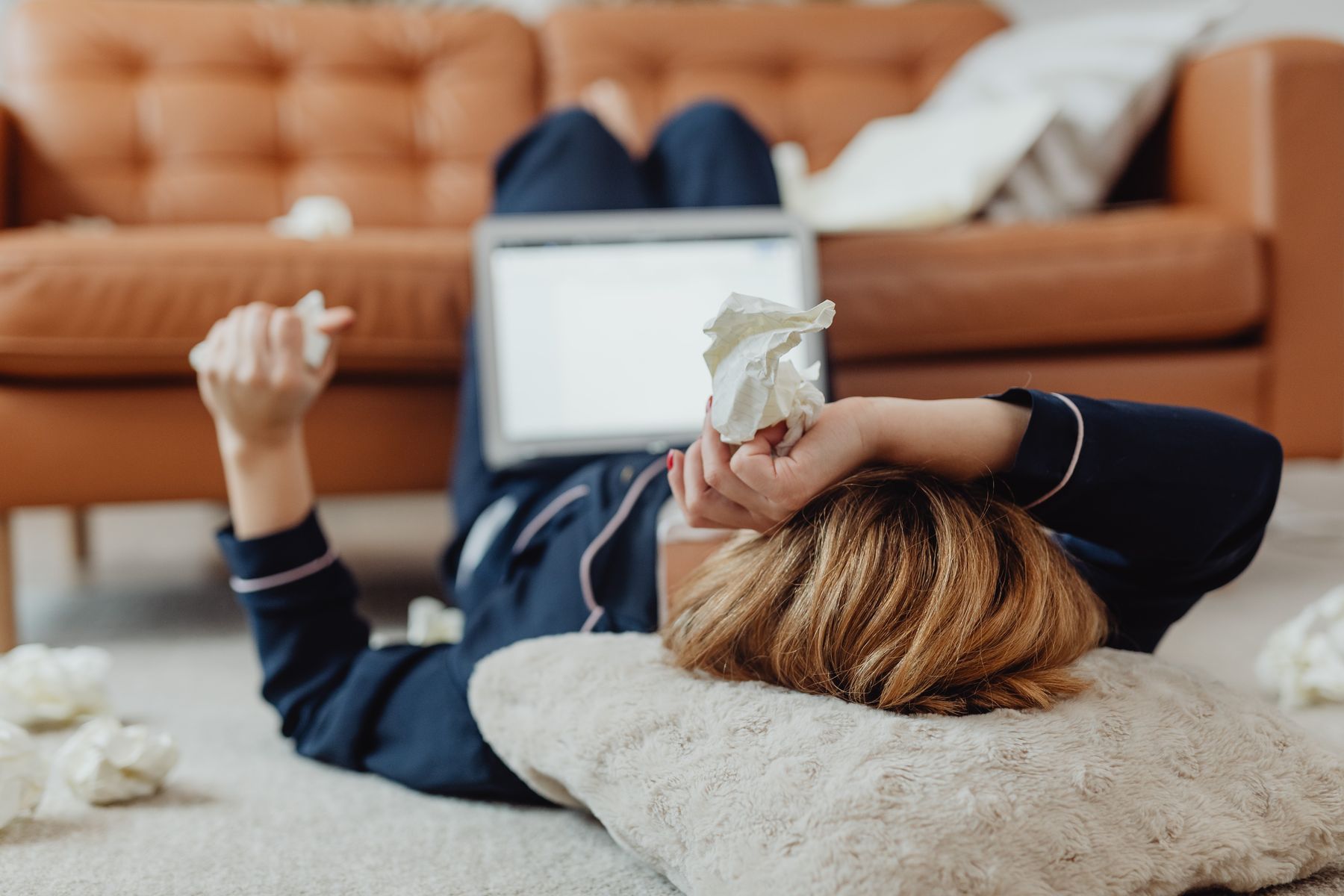 Femme allongée au sol, fatiguée, entourée de mouchoirs