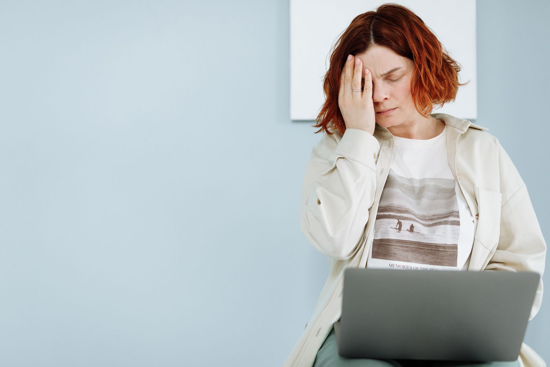 Femme stressée assise devant un ordinateur, front dans la main