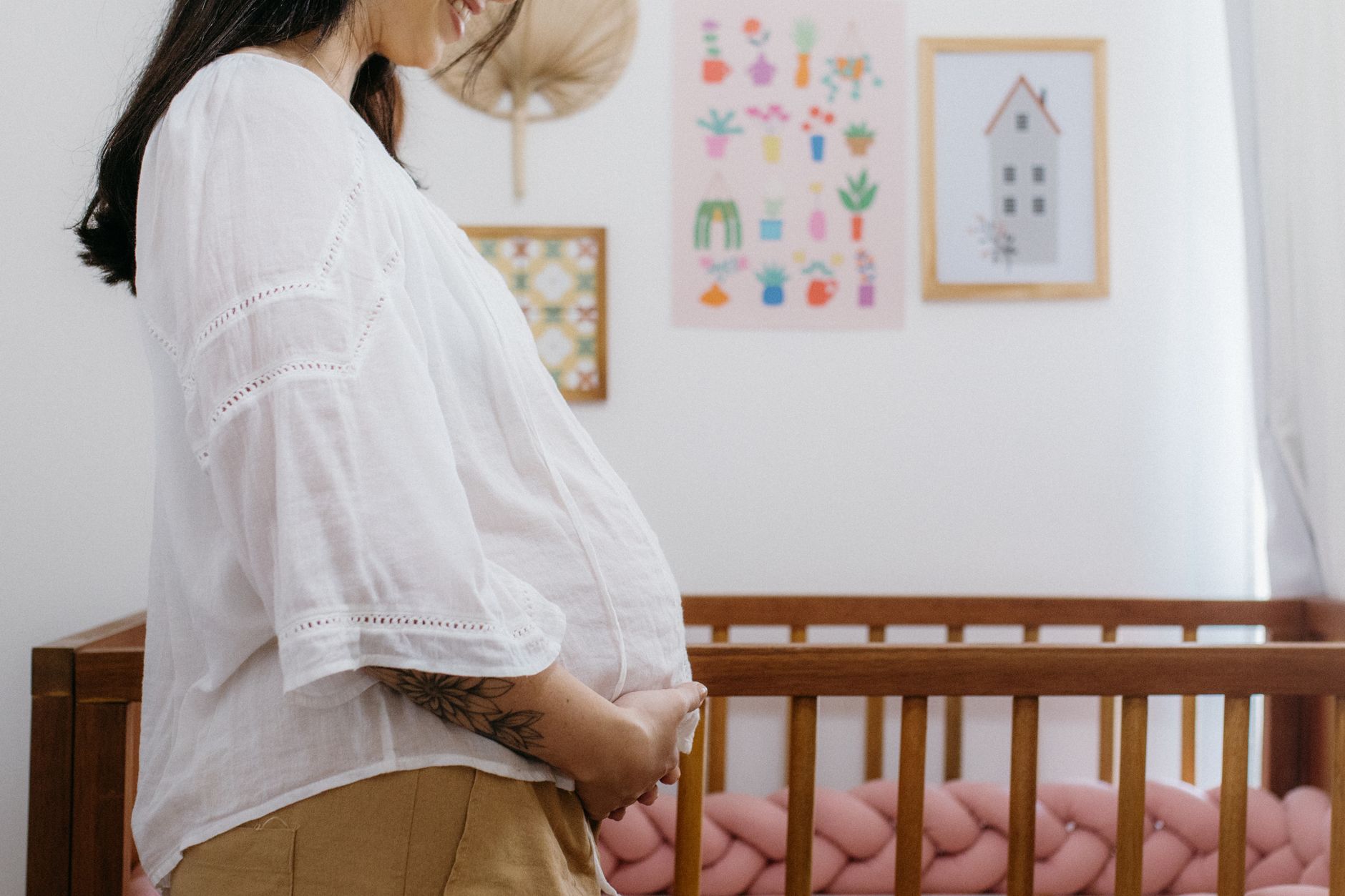Future maman debout à côté d’un berceau en bois