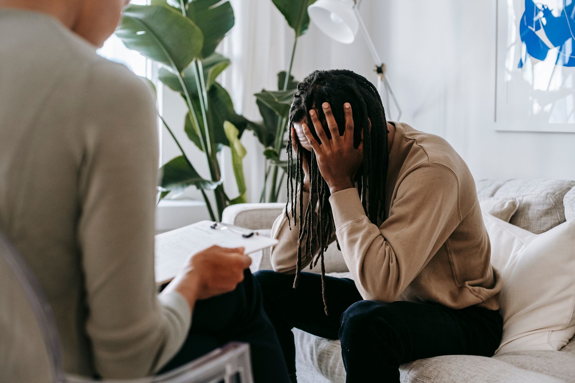 Homme anxieux la tête entre les mains lors d'une consultation avec une psychologue