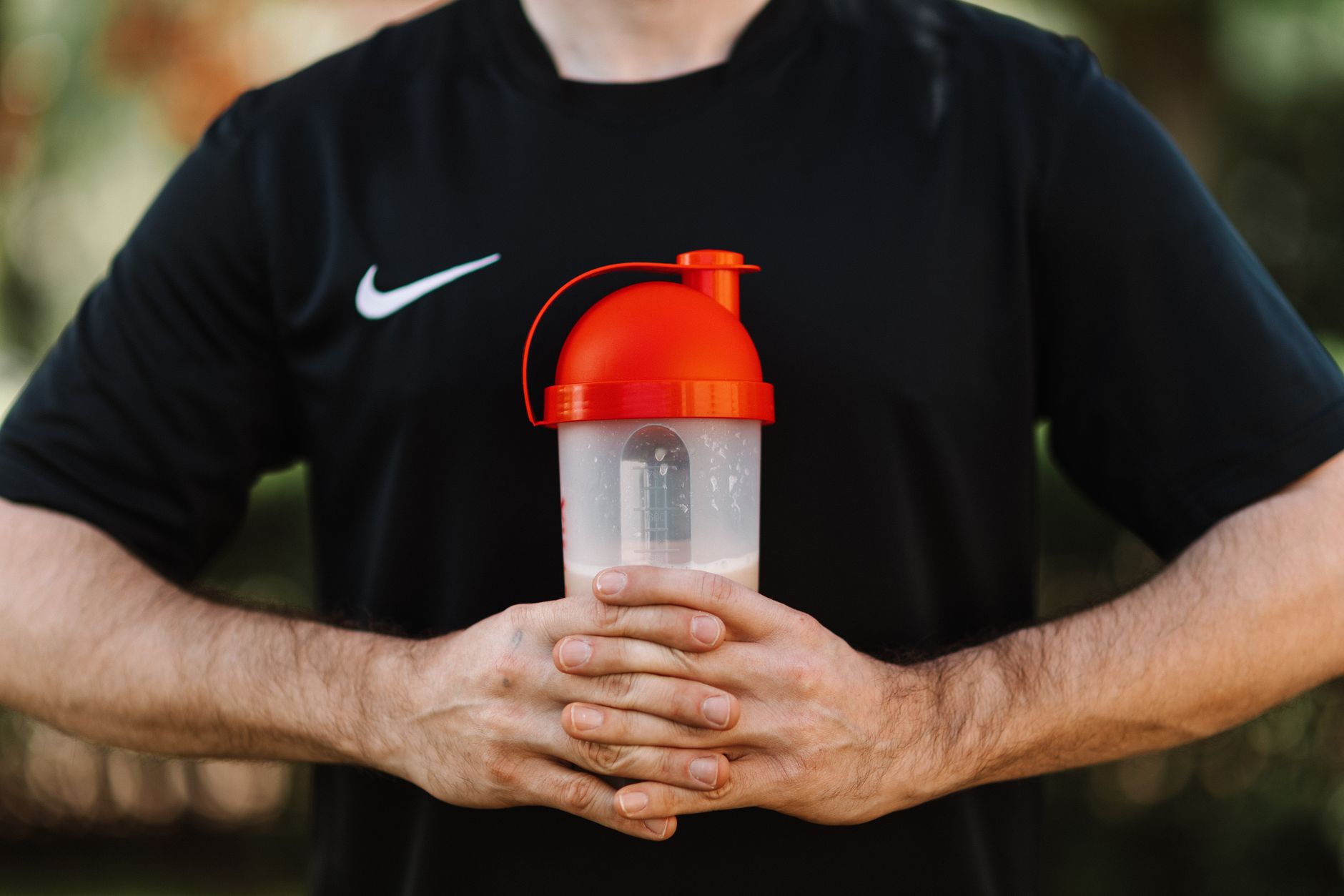 Gros plan sur un shaker de whey tenu a la main