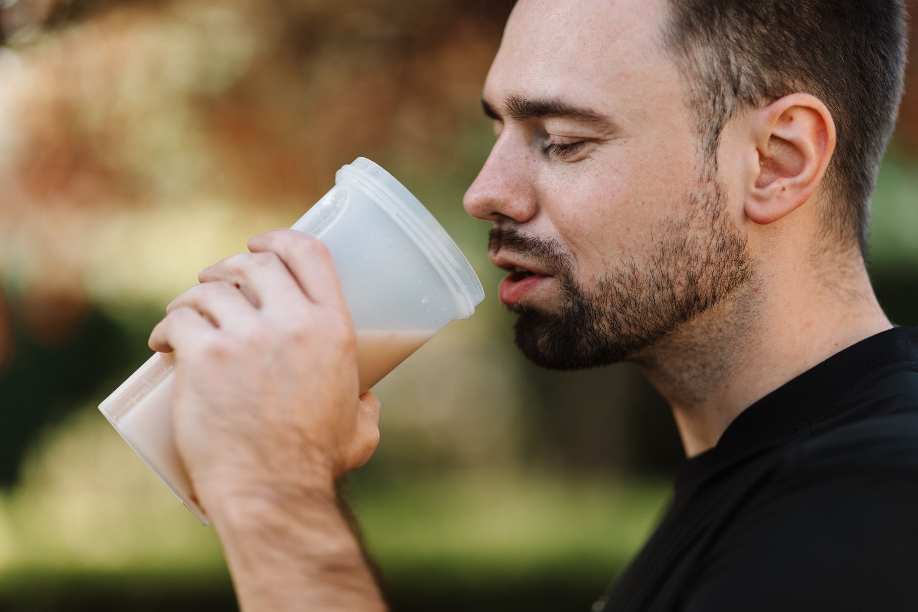 Homme buvant un shaker de whey proteinee en exterieur