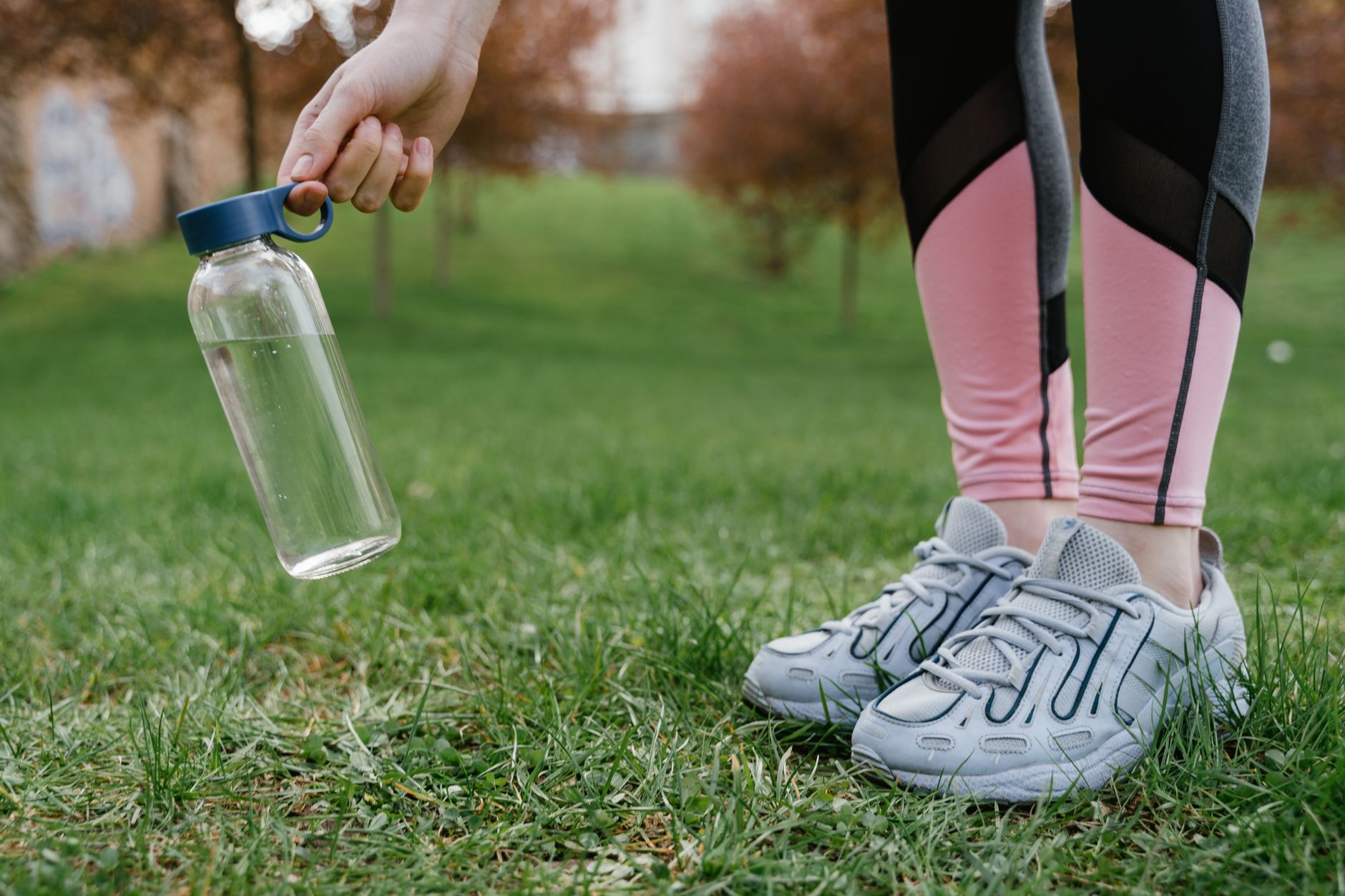 Jambes en legging rose et baskets avec un verre