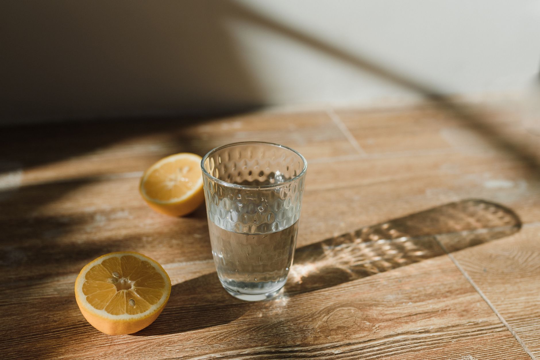 Verre d’eau citronnée posé sur une table en bois