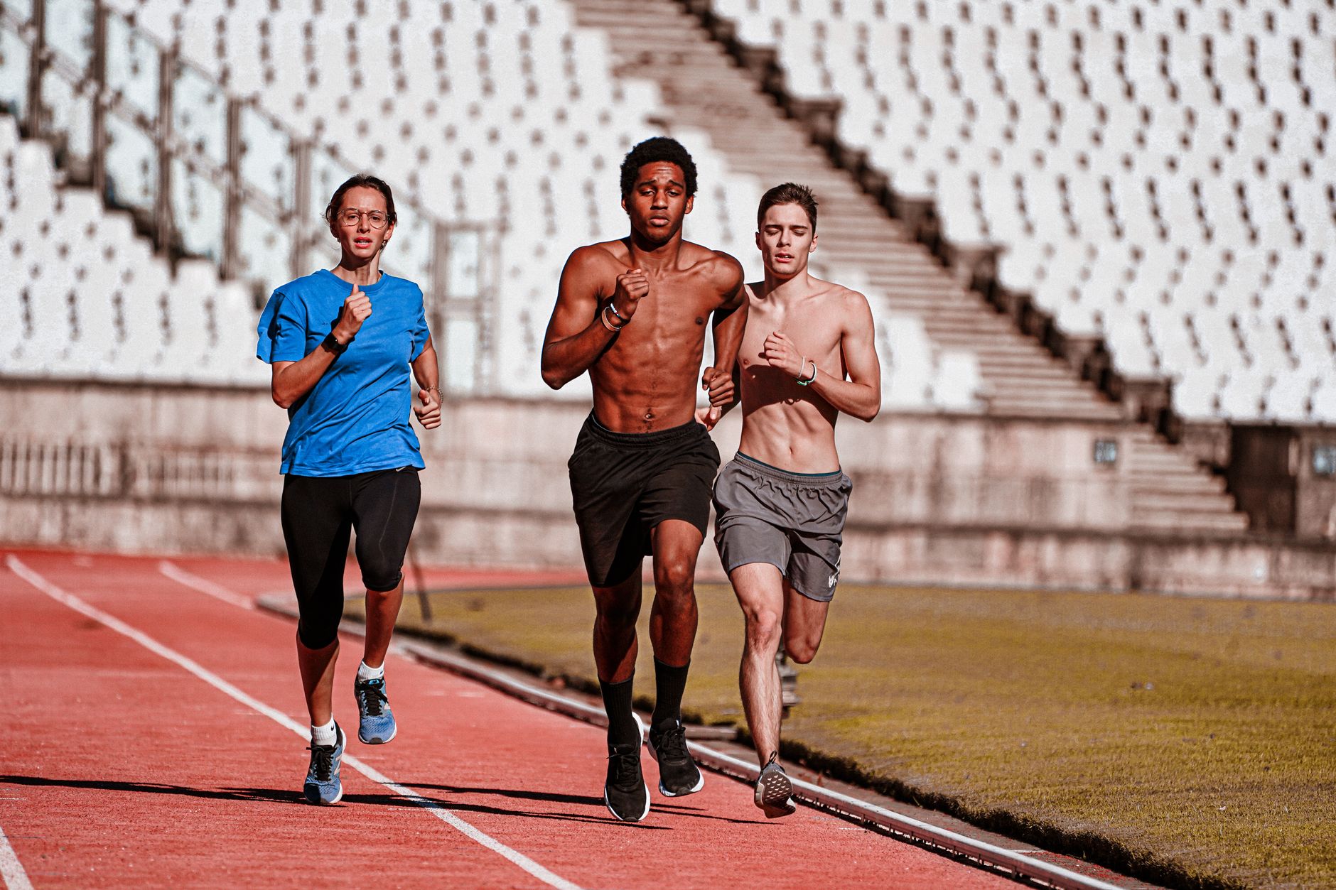 Trois coureurs sur une piste rouge de stade