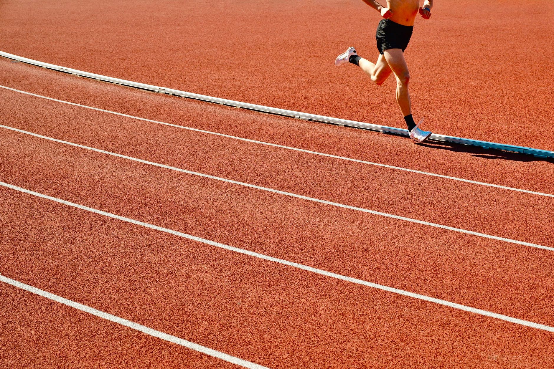 Coureur sur une piste rouge en plein soleil